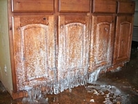 Serious water damage and ice on wooden cabinets.